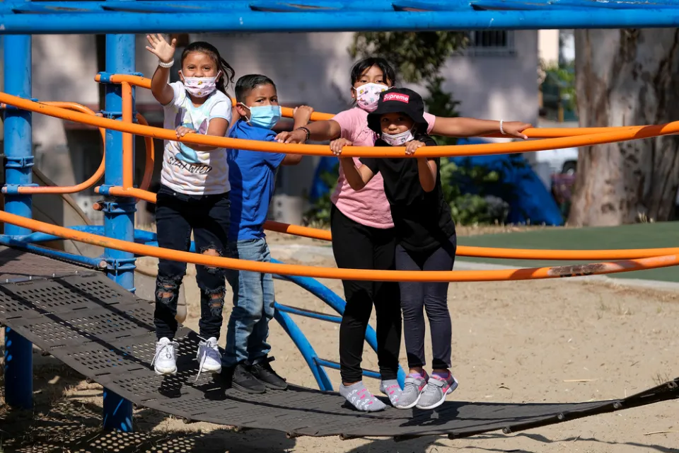 Children wearing COVID-19 masks on playground equipment
